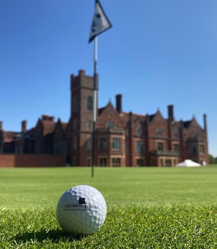 Golf ball on a green in front of Broxbournebury Mansion