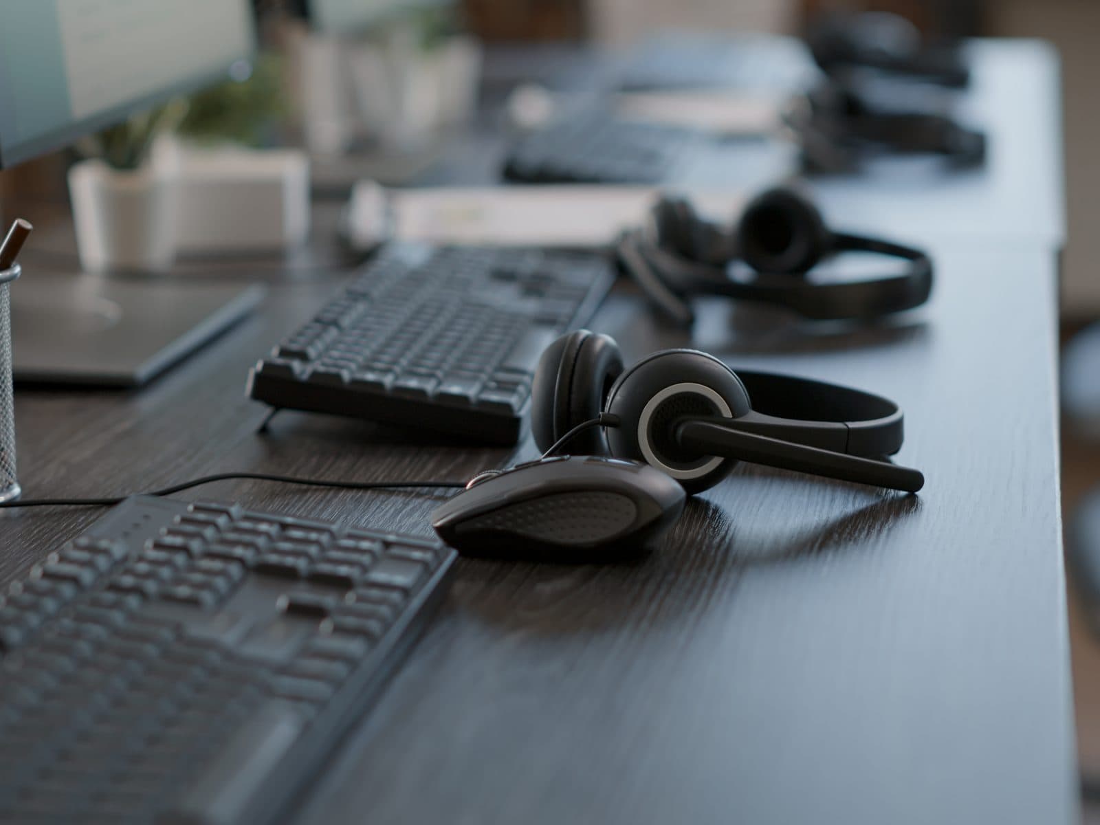 IT helpdesk workstation with headsets, keyboards and monitors